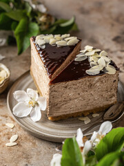 Two slices of chocolate cheesecake with almond petals on brown textured background close up. Spring flowers in blur. Menu