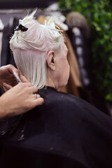 hands cutting hair of white haired woman with space for writing