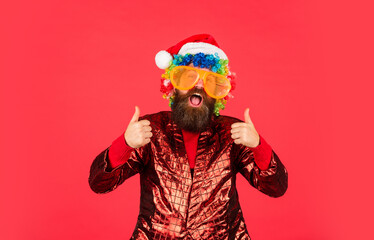 Wishing a happy New Year. happy caucasian guy await new year present. lets have fun. Santa Claus hipster. handsome man at Christmas. brutal bearded male red background. party man in Christmas glasses - Powered by Adobe