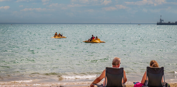 couple enjoying the afternoon on a calm and peaceful relaxing in front of the ocean view Weymouth beach England