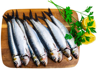 Raw sardines with lemon, parsley, garlic and spices on cutting board. Isolated over white background