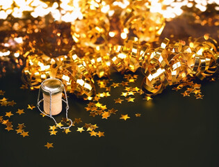 champagne cork, golden tinsel and stars confetti on shiny black abstract background. Christmas and...
