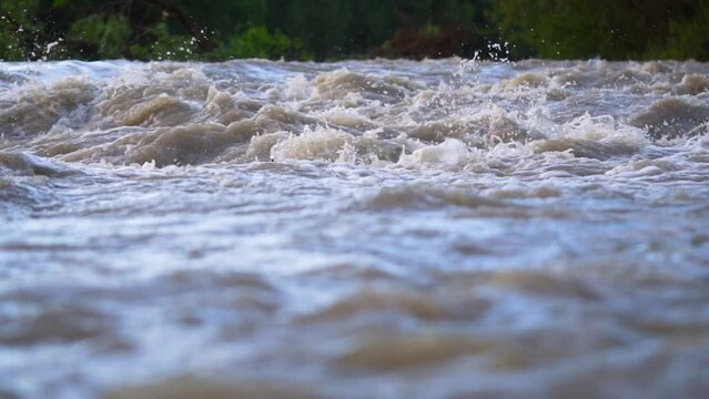 Dirty flood water flowing rapidly in river, closeup abstract detail, slow motion video