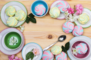 Colorful airy striped marshmallows on saucers on  a light wooden background