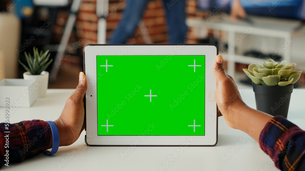 Poster young adult holding digital gadget with horizontal green screen, looking at blank background on mode