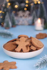 Various of Christmas sugar cookies in variety shape in a bowl with holidays decoration atmosphere and candle light, with festive ambiance. Green xmas trees branches and light bokeh in background