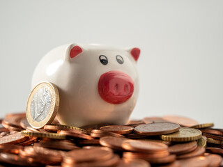 The piggy bank stands on metal coins. A bunch of euro cents and a piggy bank.