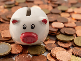 The piggy bank stands on metal coins. A bunch of euro cents and a piggy bank.