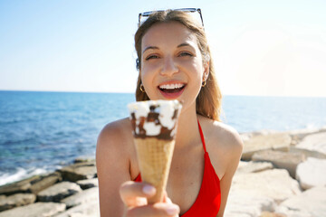 Close-up of Brazilian woman smiling at camera showing ice cream cone on the beach on summertime