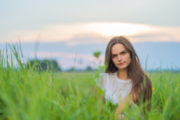 Portrait of a long-haired girl posing in a field on a summer evening.