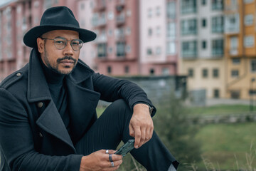 elegant latin man sitting on the street with mobile phone