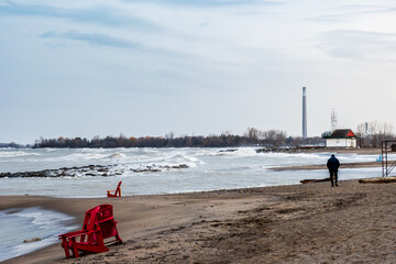 A man walks on Kew Beach on a stormy winter day in Toronto's iconic Beaches neighbourhood with the Leuty Lifeguard Station in the background..