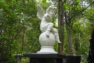 Fototapeta na wymiar Angel in the cemetery monument at the grave of a child sculpture in the form of an angel