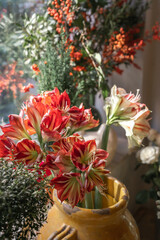 Multiple beautiful bouquets of various flowers are arranged in front of a window to create a romantic ambiance for a surprise proposal. 