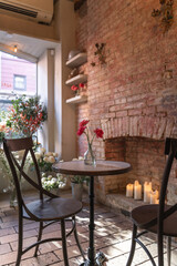 Beautiful red flowers in a vase are arranged to sit on a table creating a romantic ambiance for a surprise proposal. 