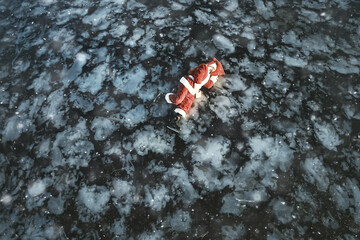 Fototapeta na wymiar Santa Claus skating on the ice of the lake, slipped, lies down, Santa loser