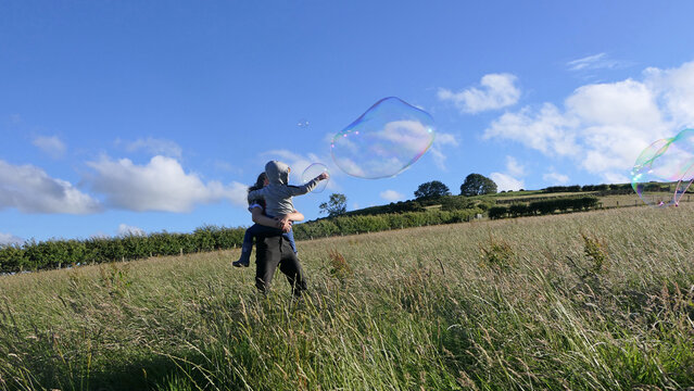 Giant Soap Bubble with a Bubble wand in field in summer