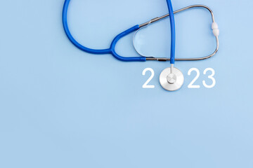 Stethoscope and numbers 2023 on blue background. The concept of health care in the New Year. Copy...