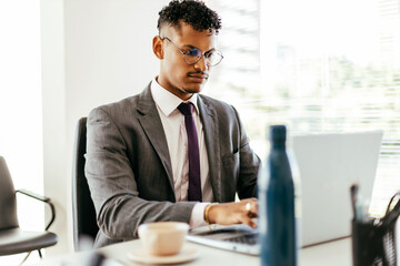 Young Brazilian businessman working on laptop in modern office