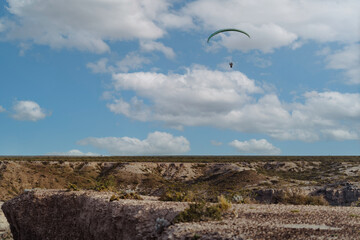 Paragliding among beautiful clouds and above desert arid area
