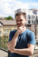 Fototapeta premium Smiling man touching his face on balcony in city