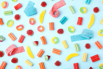 Many different jelly candies on light blue background, flat lay