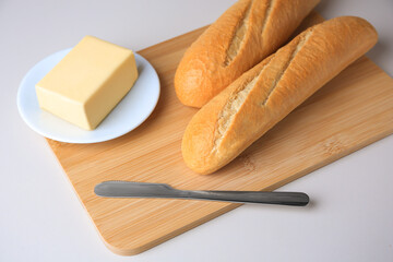 Tasty baguettes with fresh butter on white table