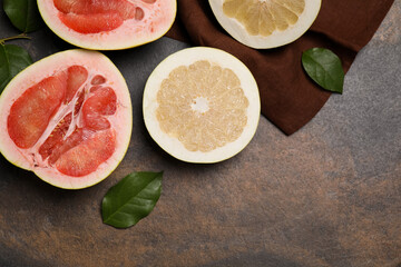 Fresh cut pomelo fruits with green leaves on dark table, flat lay. Space for text
