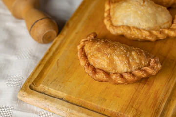 Close up of fried Argentine empanadas on a wooden board.