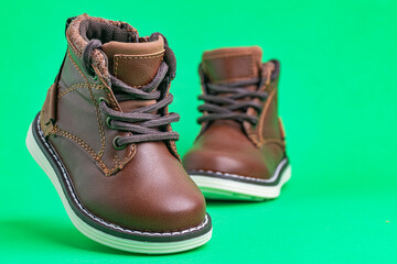 Leather children's boots with laces on green background. Modern leather children's shoes.