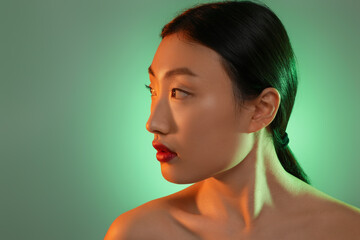 Fototapeta premium Portrait of beautiful young Asian woman on green background, space for text