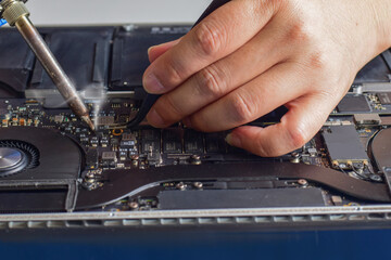computer technician A laptop motherboard repairman is using lead solder to repair some ICs for his desk. fix motherboard
