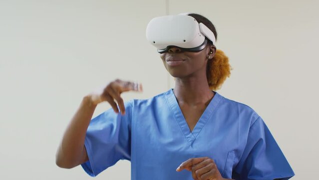 Female nurse or doctor in scrubs wearing VR headset interacting with AR technology in hospital - shot in slow motion