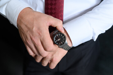 A man straightens a watch strap, close-up. Young modern businessman. Business style clothing concept, wedding