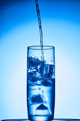 closeup of pouring water on the cup on transparent blue background