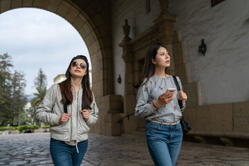 two curious asian Taiwanese female tourists walking through main arch entrance of santa Barbara...