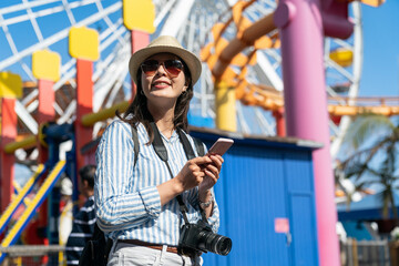 portrait of cheerful asian Taiwanese girl backpacker wearing sunglasses exploring in amusement park...