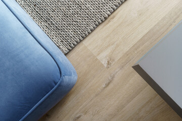 Fototapeta na wymiar corner of blue sofa, floor rug and table in living room, above view