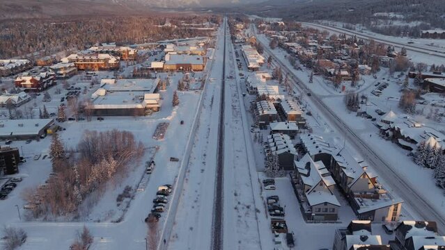 Drone flying over main rail line in  Canmore, Alberta. Towering Rocky mountains in the distance.