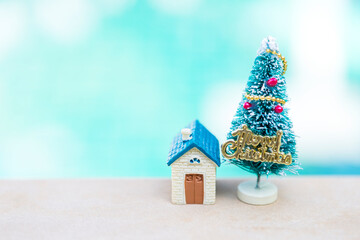 Christmas concept background, miniature house with Christmas tree over blurred background
