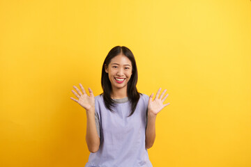 Young women waving hands to greeting and smiling with happiness on isolated yellow background