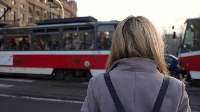 The girl stands against the background of a passing tram on the street. public transport