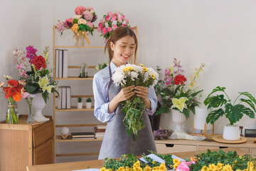 Floristry concept, Woman florist smiling and holding white and yellow chrysanthemum in flower shop