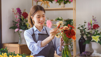 Florist concept, Woman florist arranged colorful gerberas in glass vase for customer at flower shop