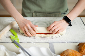 Woman hands with electronic bracelet cooking homemade pastry on silicone baking mat with markers.