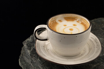 Cup of coffee with foam muzzle on a black background.
