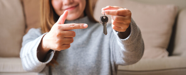 Closeup image of of a woman holding and pointing finger at the keys for real estate concept