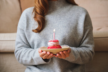 Closeup image of a young woman holding birthday cake with candle