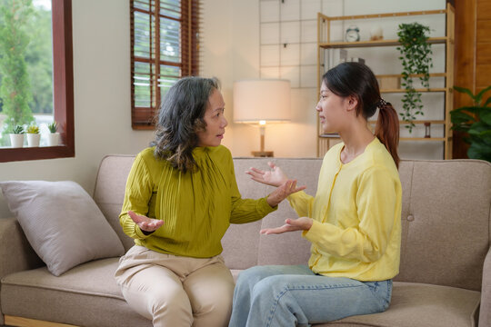 Asian mother and daughter spend their vacation in the living room not talking to each other and angry with each other Both of them showed emotion to each other.