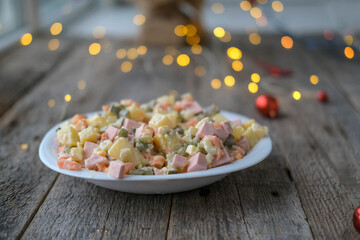 Homemade New Year is Olivier salad on a wooden background. A plate of traditional Russian Christmas salad.